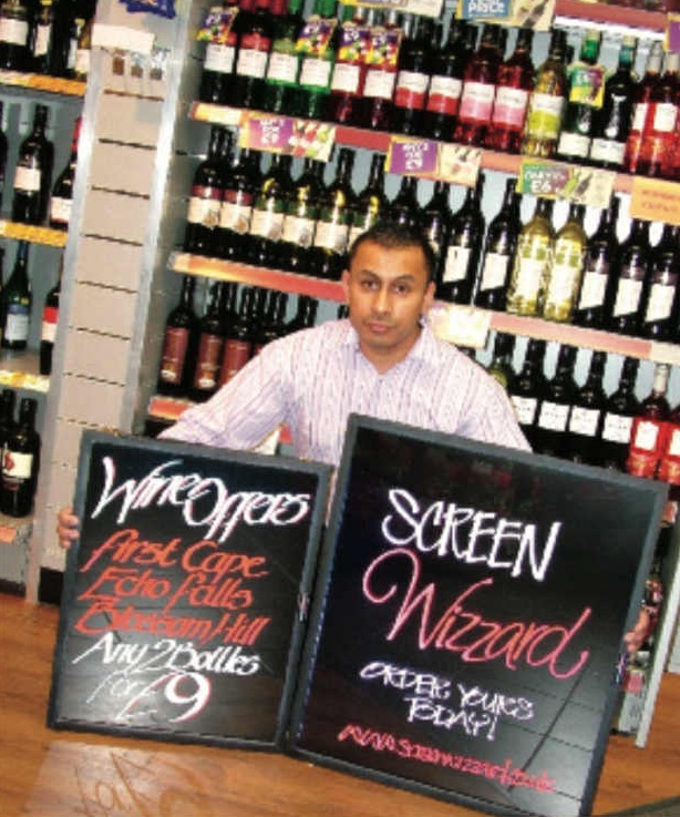 Man holding wine sale signs in a liquor store.