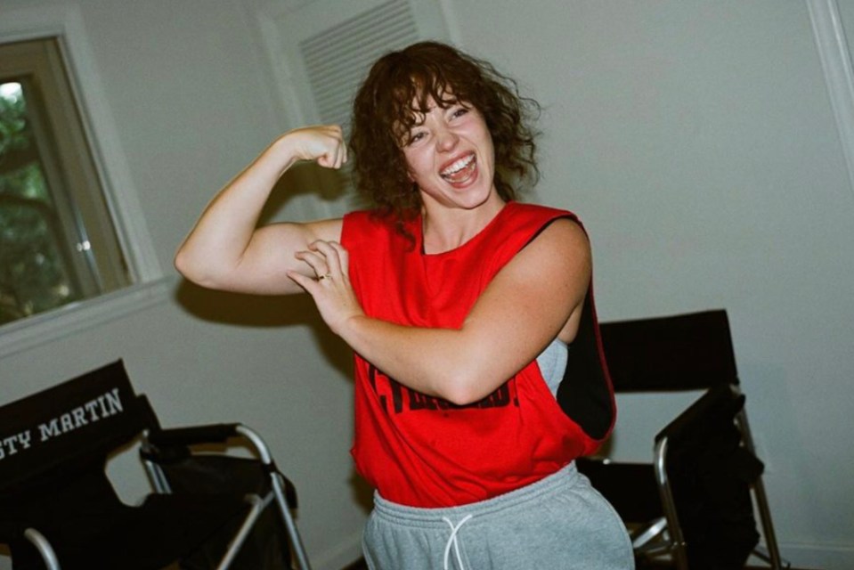 Sydney Sweeney flexing her biceps while wearing a red tank top.