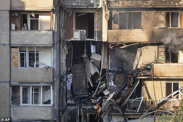 A local resident looks out of the balcony in the damaged multi-storey building after Russia's drone and missile attack -- September 7, 2025