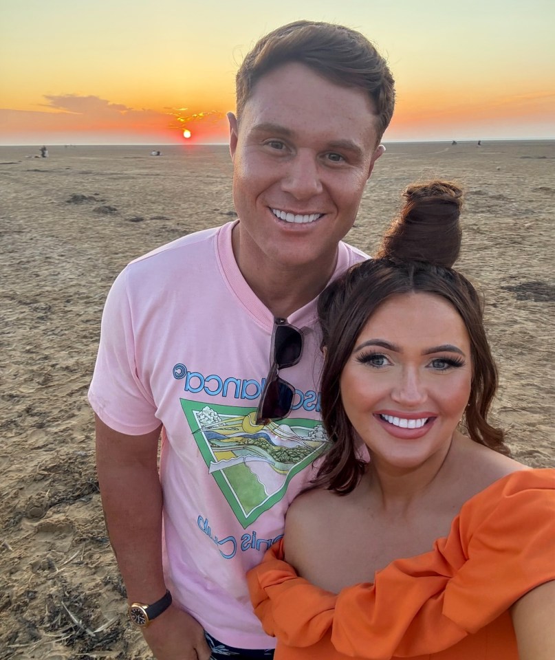 Couple posing on a beach at sunset.