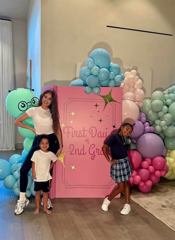 Khloe Kardashian and her children posing for a "First Day of 2nd Grade" photo.
