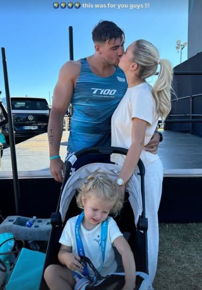 Tommy Fury and Molly-Mae Hague kissing, with their daughter in a stroller.