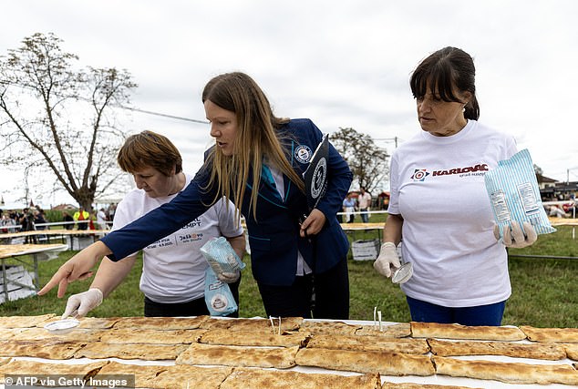 Official Guinness World Record adjudicator Paulina Sapinska (C) is instructing two woman sprinkling powdered sugar on strudels during the Guinness World Record attempt