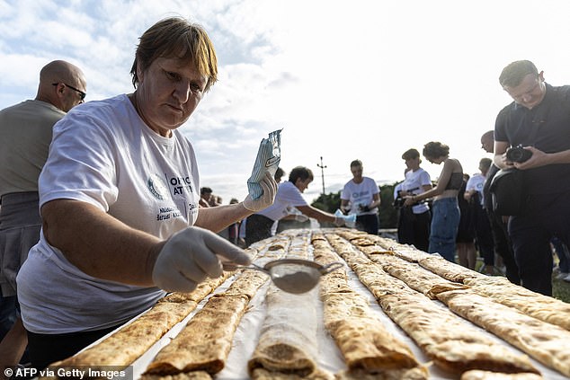 A woman sprinkles powdered sugar on strudels during the Guinness World Record attempt