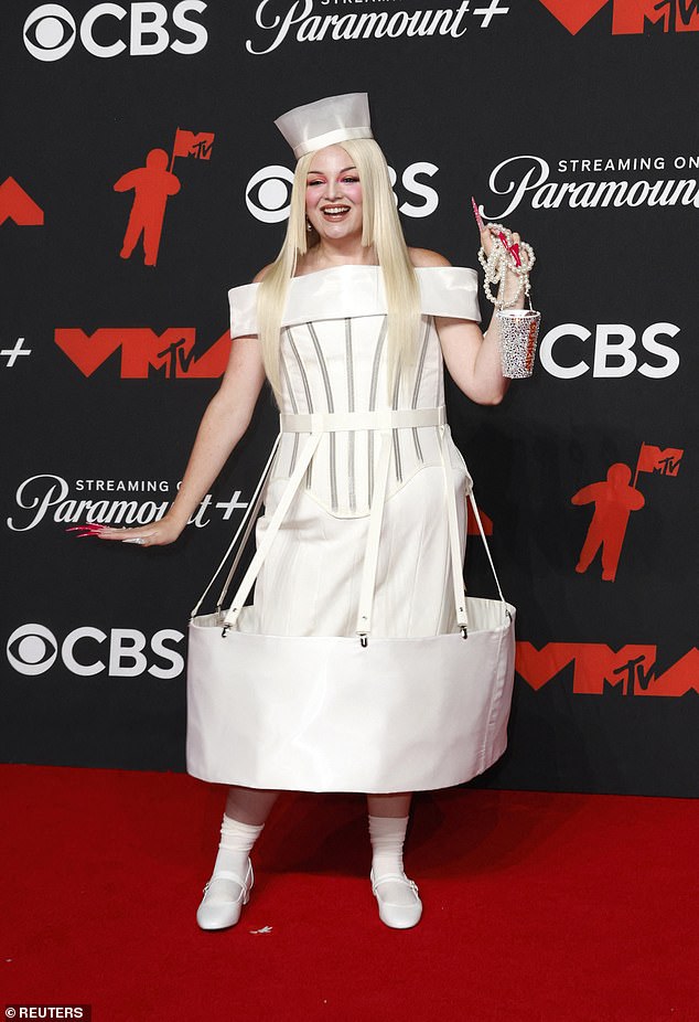 Actress and comedian Megan Stalter wore a white gown that had a large round piece of fabric at the end of the skirt. She paired the strange ensemble with a bedazzled Dunkin Donuts bag