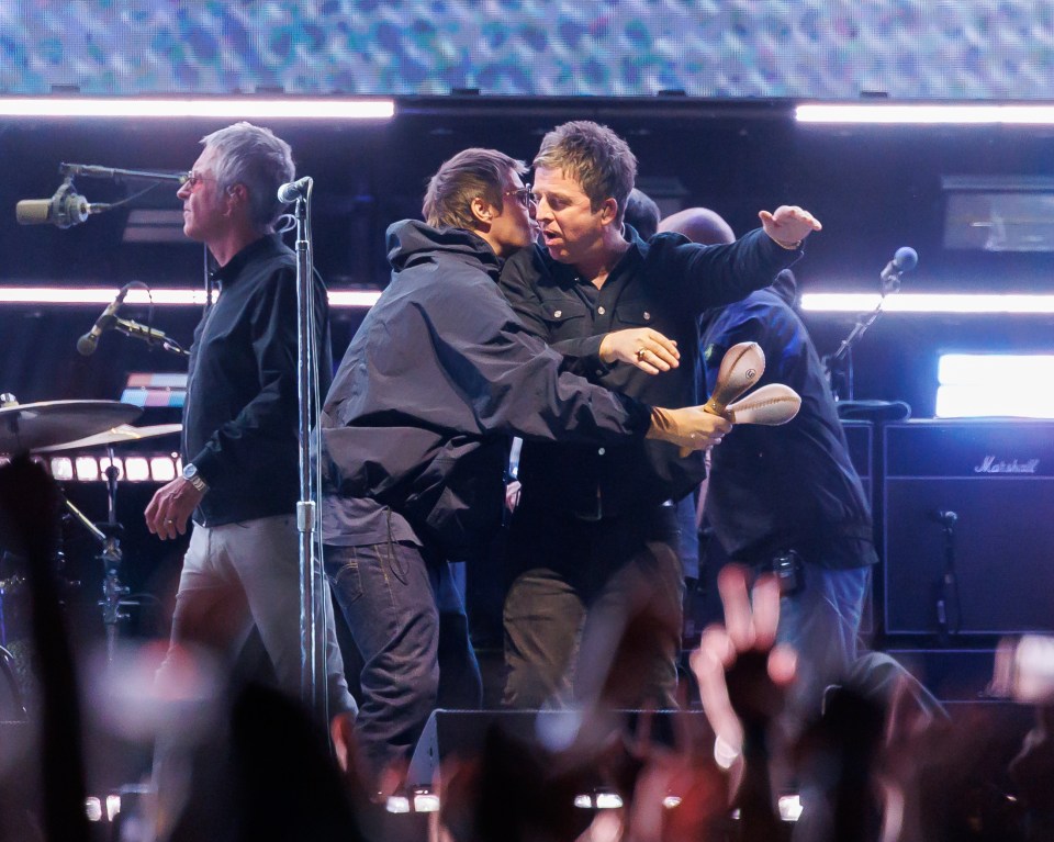 Liam and Noel Gallagher of Oasis embracing onstage.
