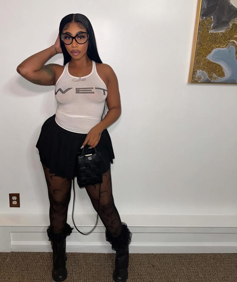 Lola Doll wearing a white tank top, black skirt, patterned tights, and black boots.