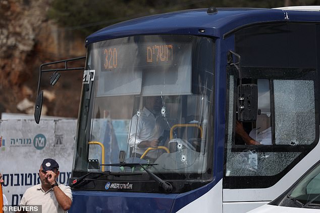 A bus with bullet holes in the windscreen is inspected. The shooting took place at a major intersection at the northern entrance to Jerusalem