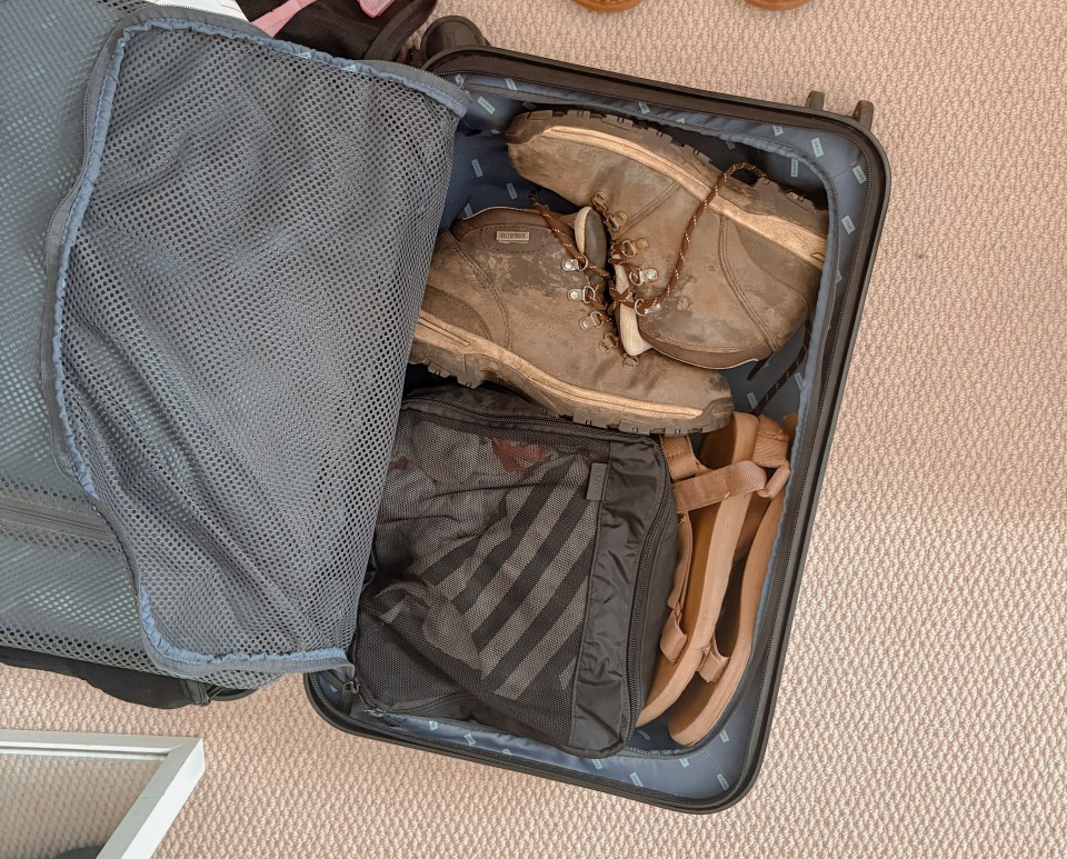 Packed suitcase with hiking boots and sandals.
