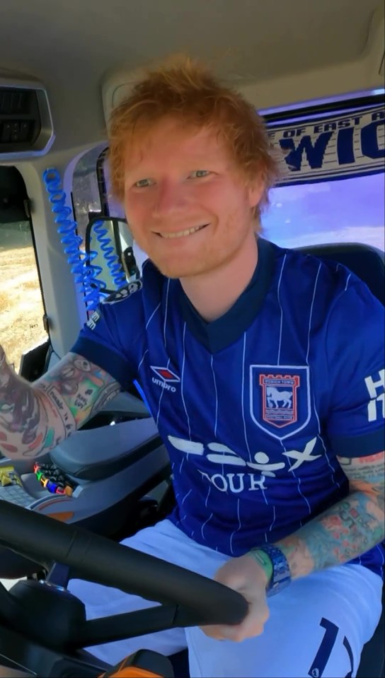 Ed Sheeran in a tractor wearing an Ipswich Town football jersey.