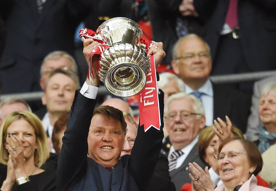 Louis van Gaal holding the FA Cup trophy aloft.
