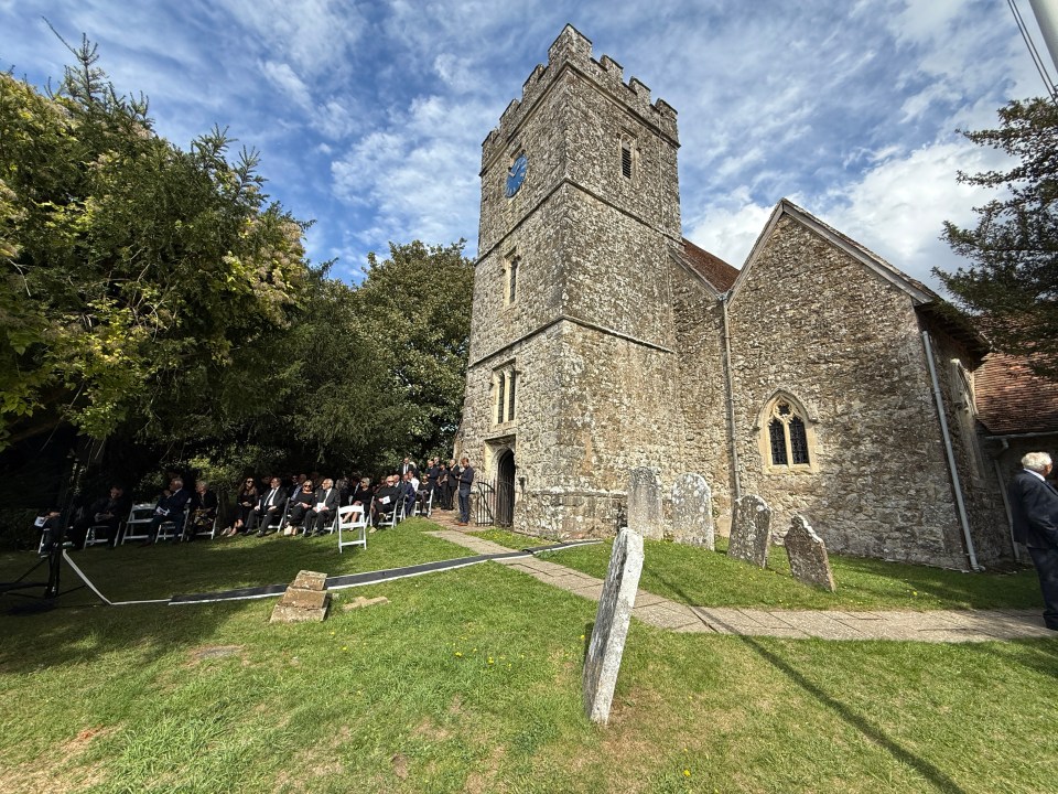 Funeral attendees outside a stone church.