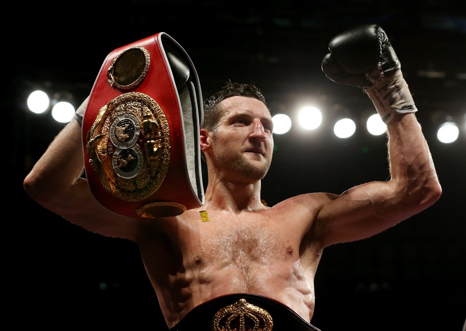 Carl Froch celebrating a boxing victory, holding championship belts aloft.