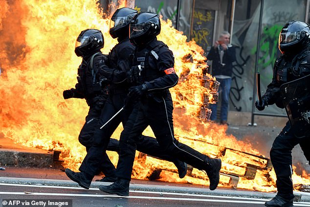 French riot police run past a fire during a demonstration in Paris on March 23, 2023