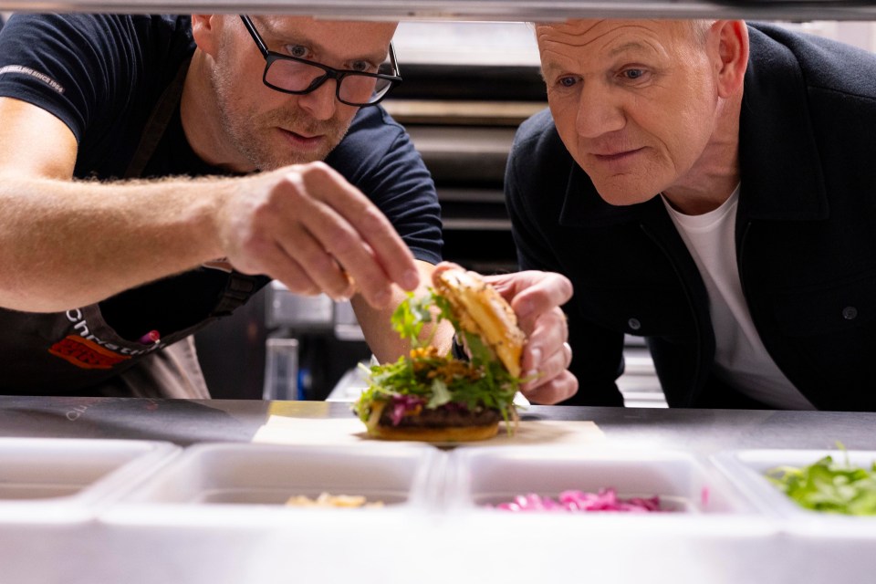 Two chefs inspecting a burger.