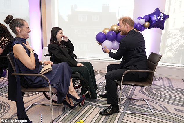 Prince Harry, Duke of Sussex, laughs with 13-year-old Grace Tutt (centre), recipient of the Special Recognitions award