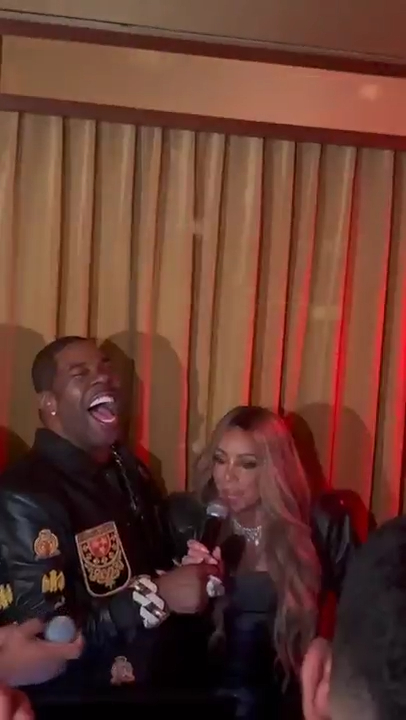 Mariah Carey and a man laughing at an afterparty.