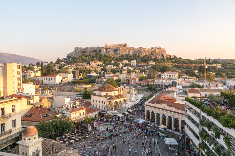 Elevated view of Monastiraki Square in Athens, Greece, at sunset, with the Acropolis in the background.