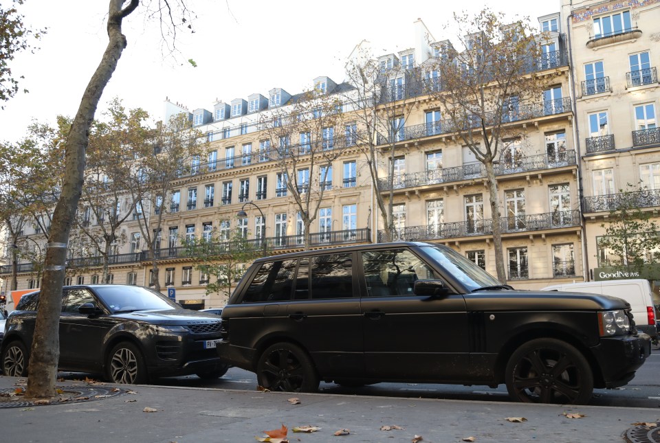 Two black SUVs parked on a Parisian street.