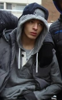 a young man wearing a hooded jacket is sitting on a bicycle .