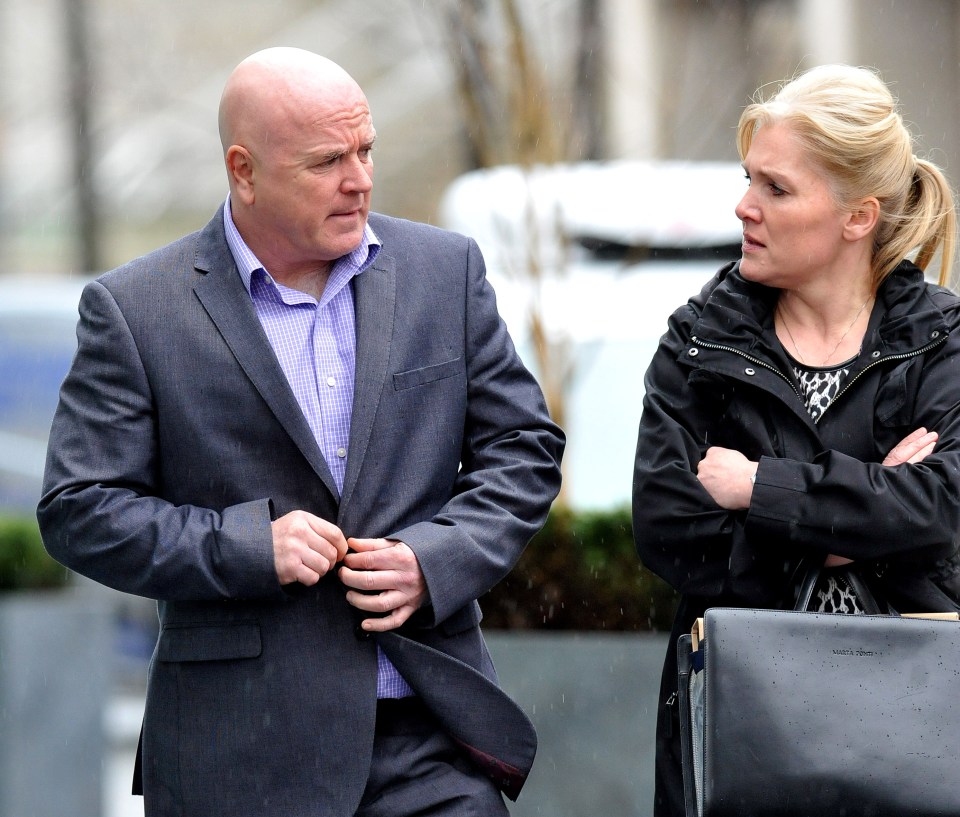 a man in a suit and a woman in a black jacket are standing next to each other