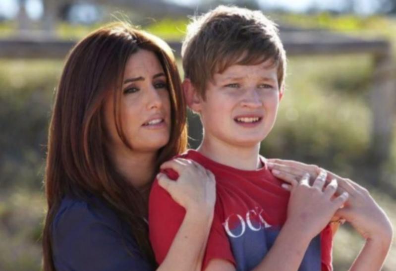 a woman holds a boy who is wearing a shirt that says oc