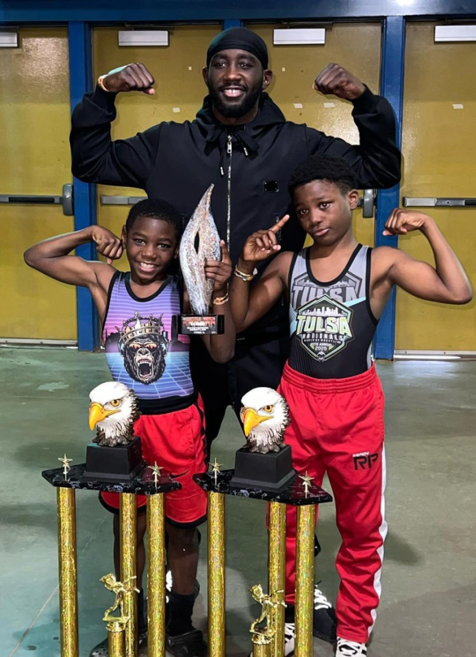 Man and two boys flexing with trophies.