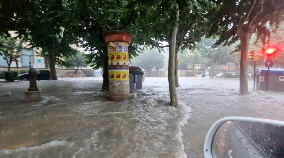 Floodwaters in a city street during heavy rain.