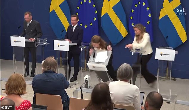 The minister is seen toppling the lectern over as she falls unconscious