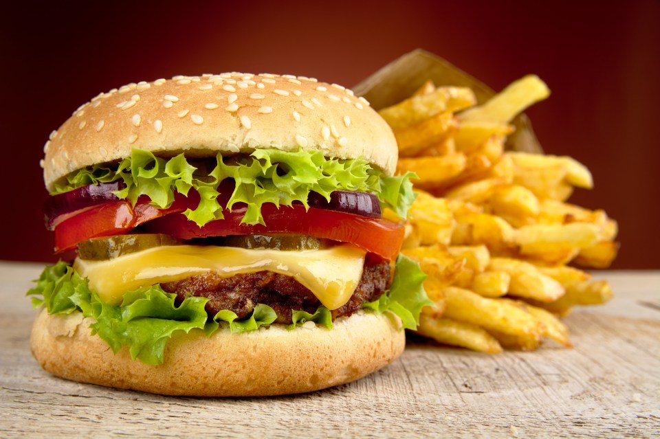 Cheeseburger and french fries on a wooden table.