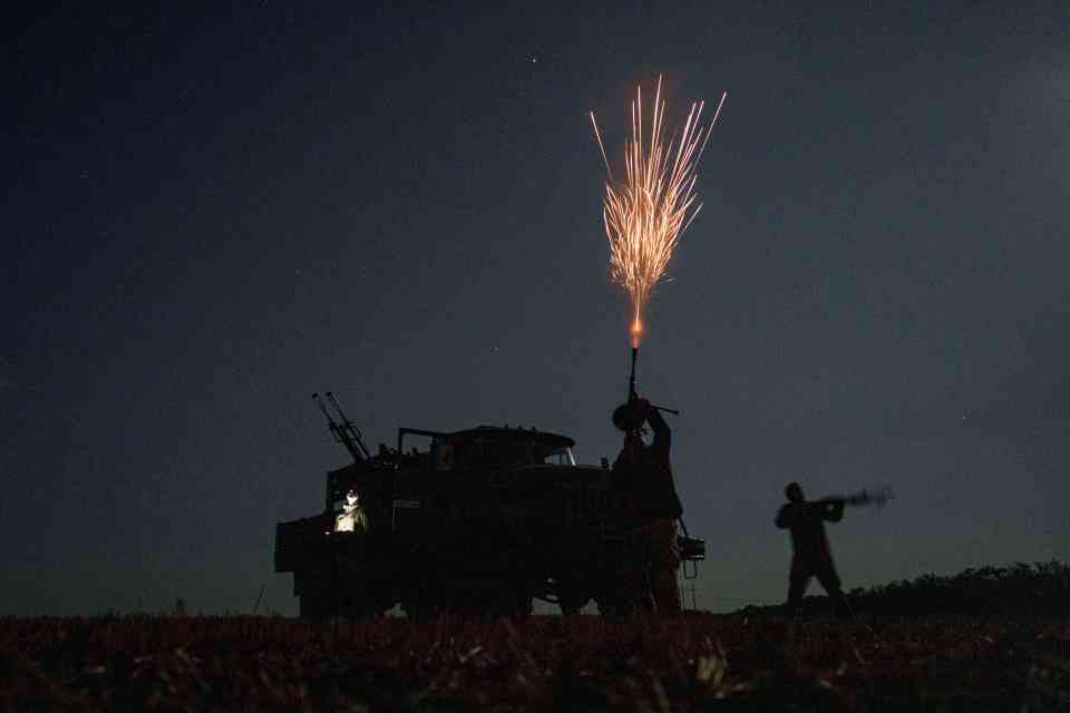 Ukrainian soldiers firing on Russian drones at night.