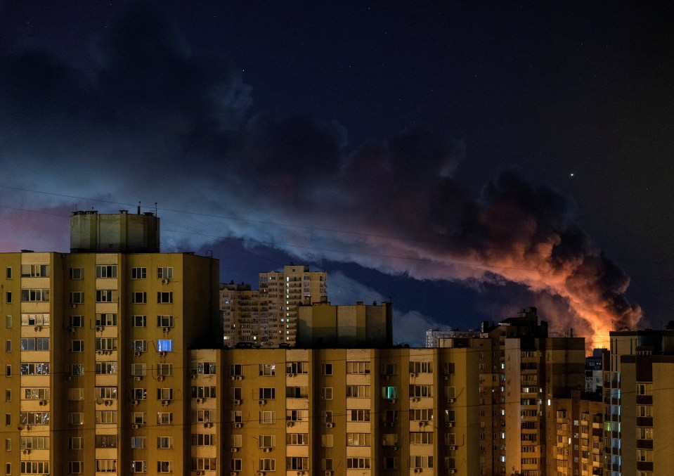 Smoke and fire rise over a city at night.