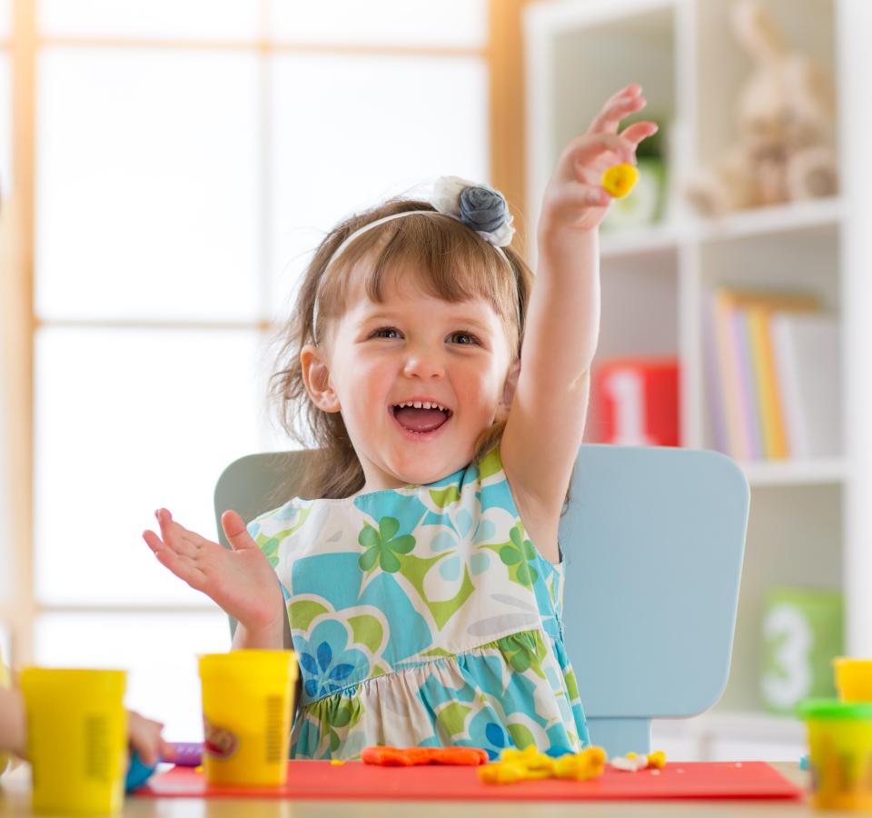 Smiling girl playing with playdough.
