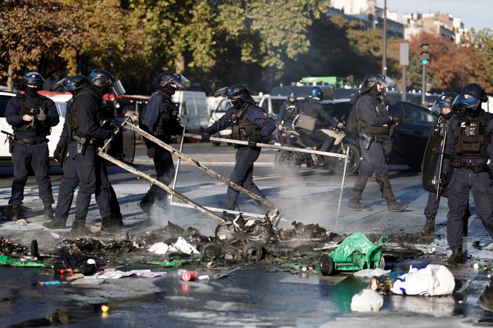 French riot police remove burnt debris from a barricade during a student protest.