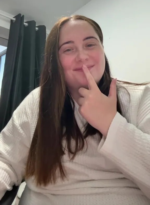 Woman smiling and touching her nose.