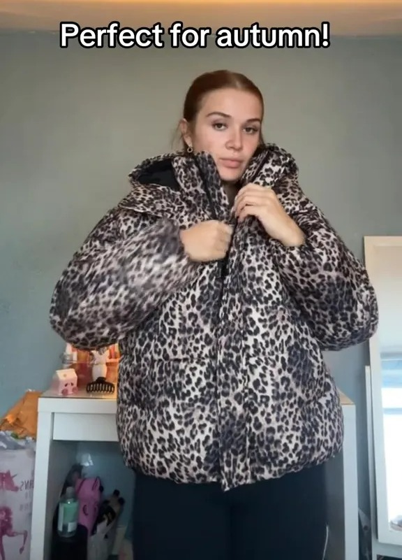 Woman modeling a leopard print puffer jacket.