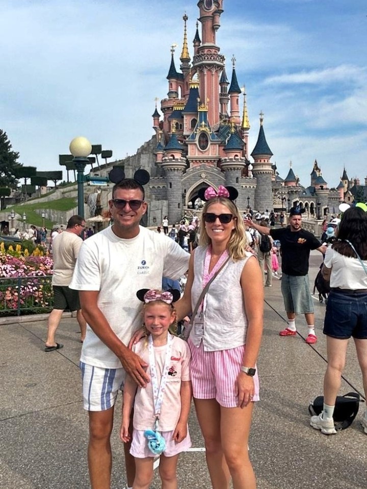 Family posing in front of Sleeping Beauty Castle at Disneyland Paris.