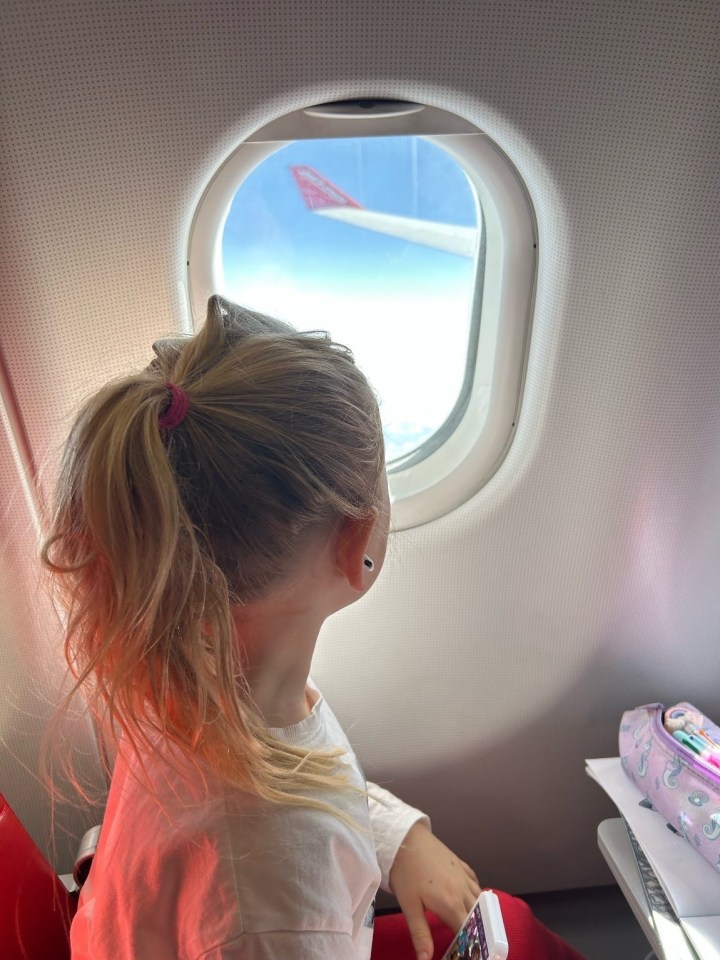 Girl looking out airplane window.