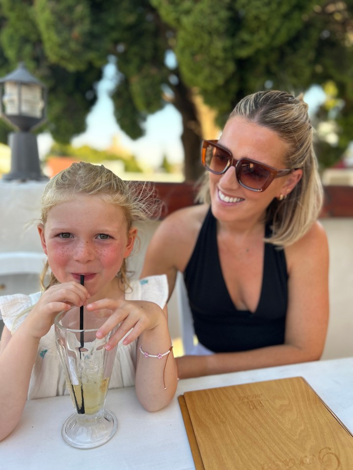 A mother and her young daughter enjoying drinks at an outdoor cafe.