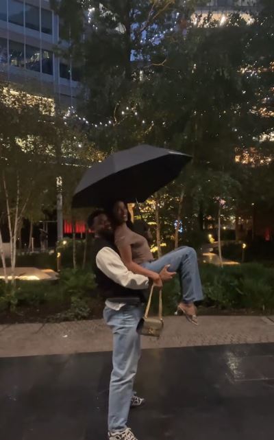 Man carrying woman under umbrella at night.