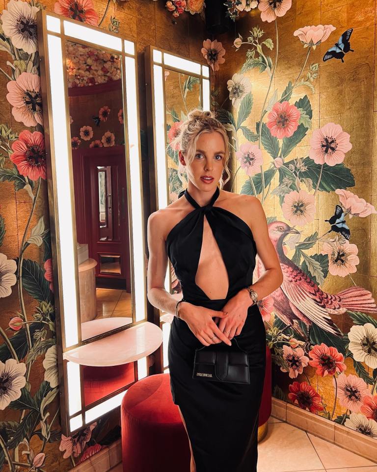 Keely Hodgkinson in a black dress, posing in front of a floral wall.