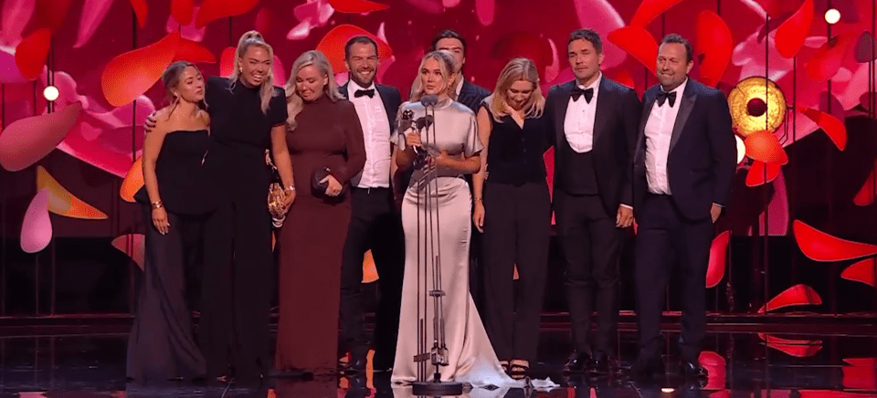 Group of people accepting an award on stage.