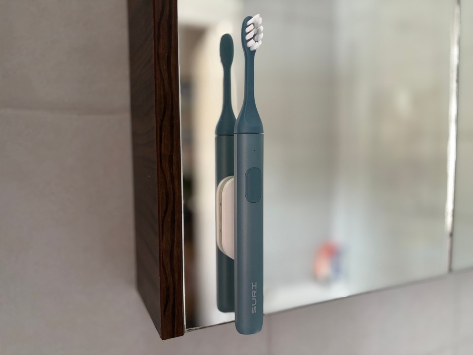Suri electric toothbrush mounted on a bathroom mirror.