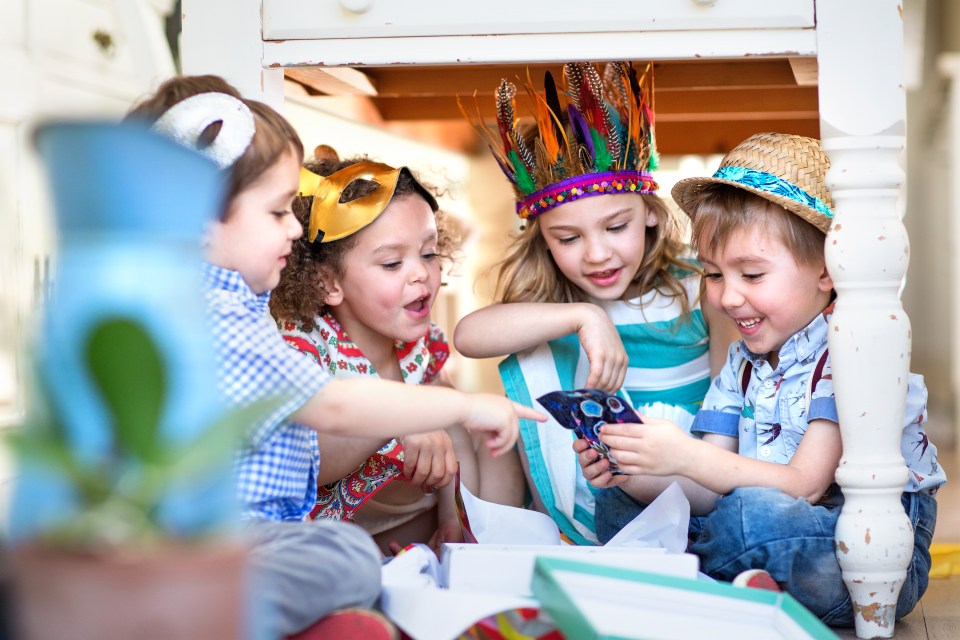 Four children opening presents at a birthday party.
