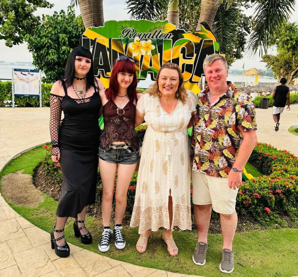 Family posing in front of a Jamaica sign.