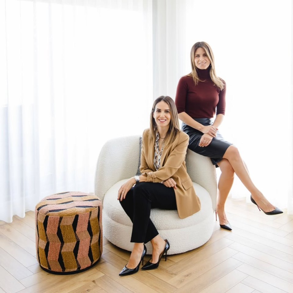 Two women in business attire pose for a photo.