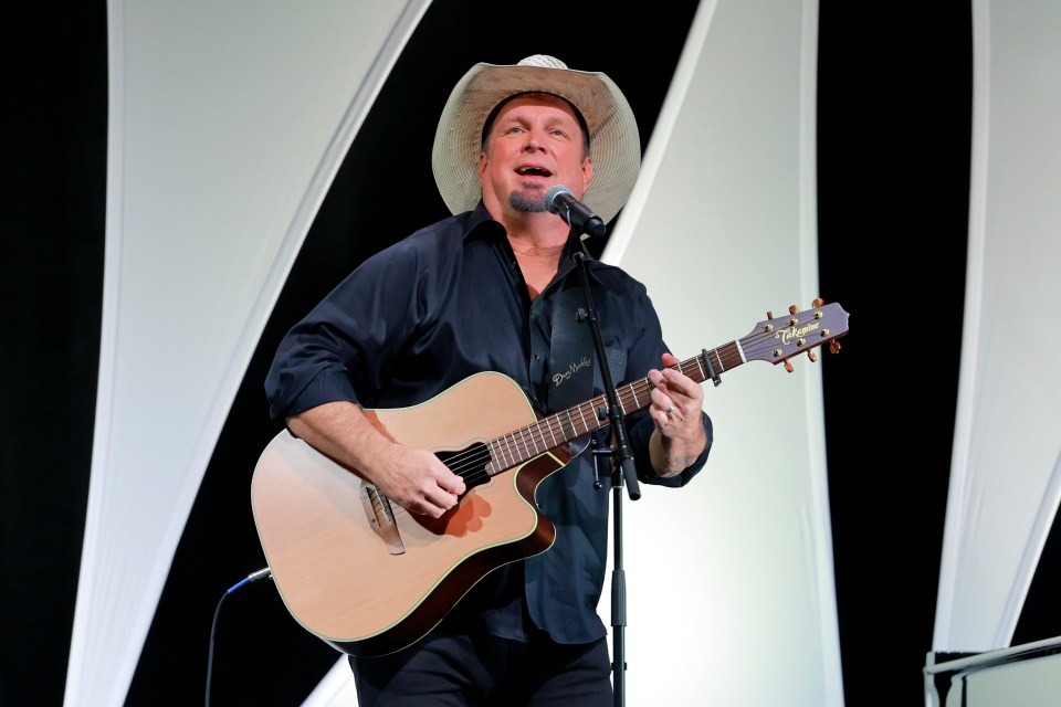 Garth Brooks performing onstage with a guitar.