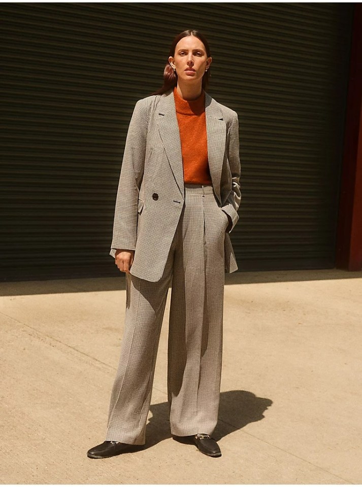 Woman in a brown and white checked blazer and pants.