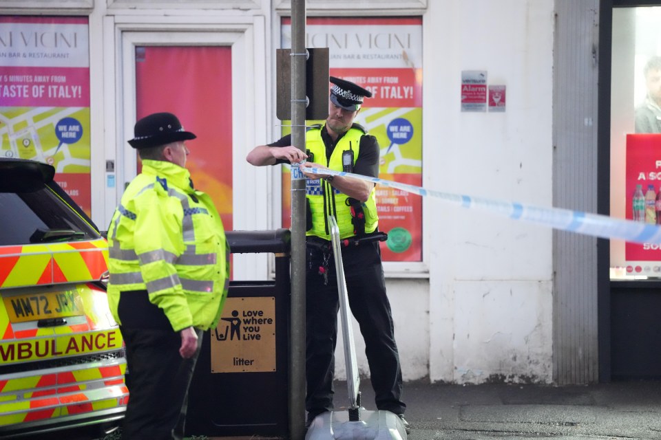 Police officers putting up police tape at a crime scene.