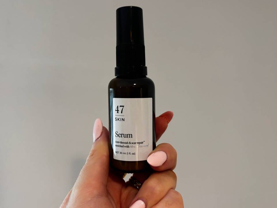 Hand holding a bottle of 47 Skin serum.